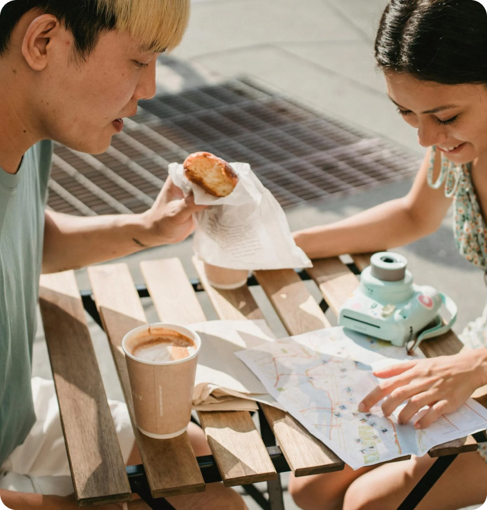 Two young men looking at a map and drinking coffee